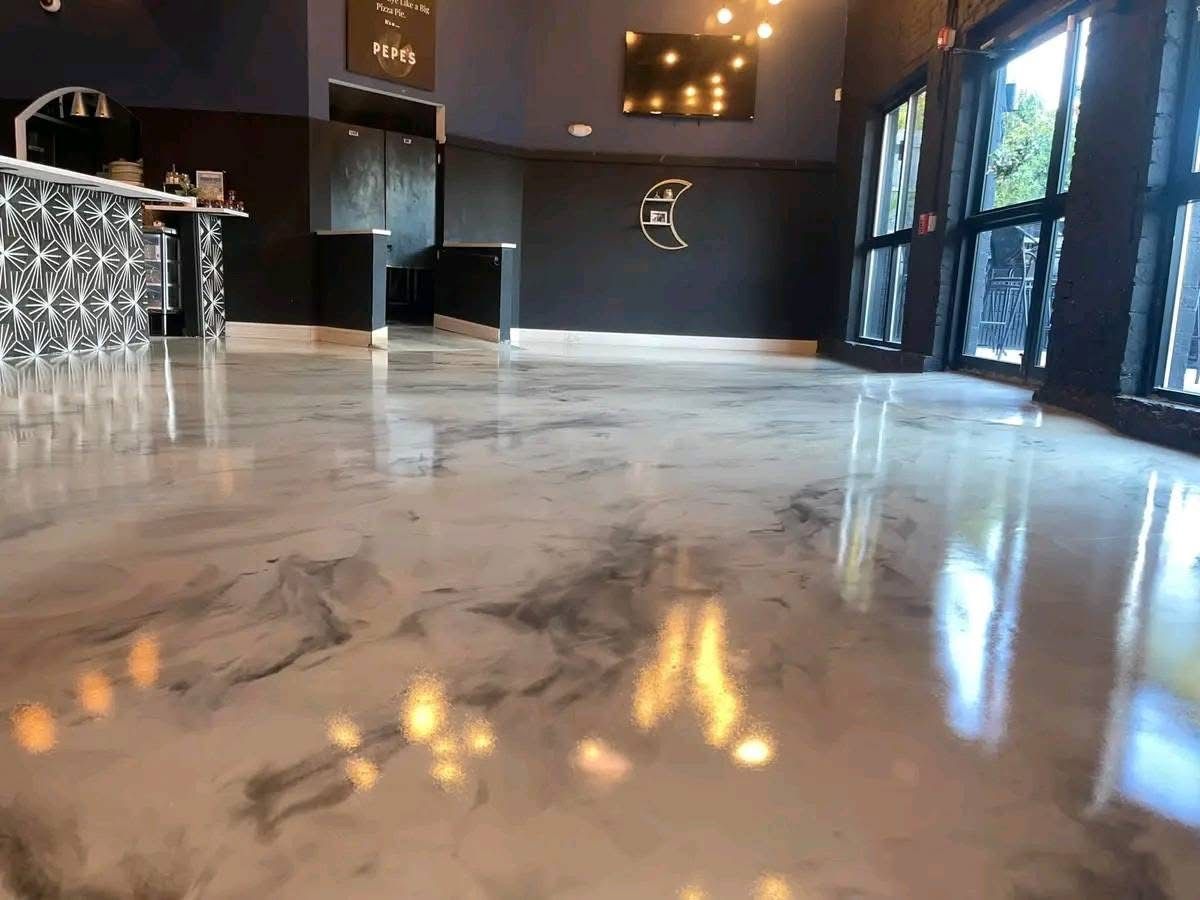 Charcoal metallic epoxy floor reflecting warm lighting in a completed K20 lounge project