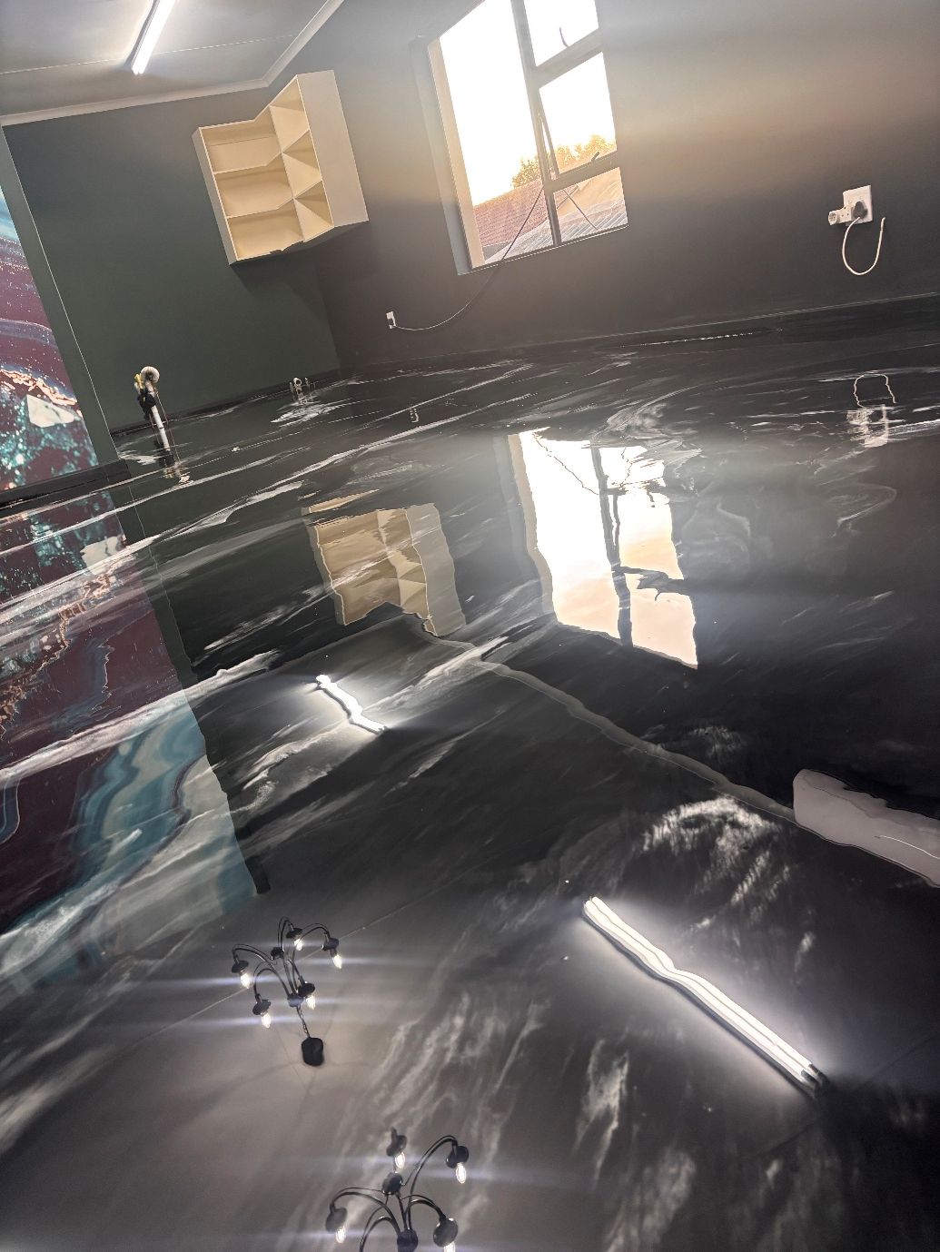 Black metallic epoxy floor with white veining reflecting the room interior